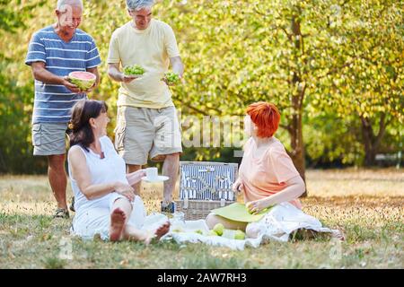 Un groupe heureux d'aînés fait un pique-nique avec des fruits dans le jardin Banque D'Images