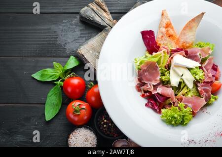Salade de légumes au fromage brie et au prosciutto. Dans la plaque. Vue de dessus. Espace libre pour votre texte. Style rustique. Banque D'Images