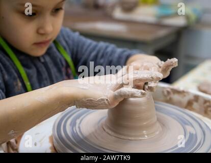 Fille de 6 ans travaille sur une roue de potter, maître de classe dans un atelier de poterie Banque D'Images