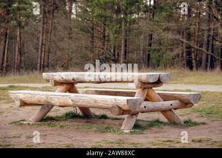 Combinaison rustique de table et de banc en bois faite de troncs d'arbres sur un pré devant une forêt. Vu en Allemagne en janvier Banque D'Images