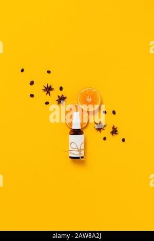 Soins naturels du corps. Bouteille de verre pour parfum, huile ou lotion corporelle entourée de tranches d'orange, cannelle, grains de café situés sur fond jaune. F Banque D'Images