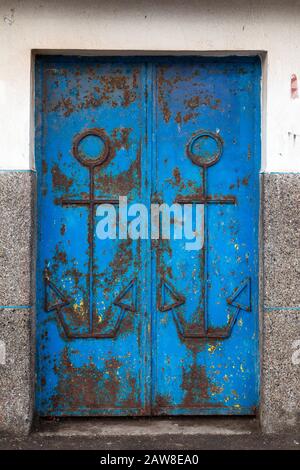 Porte en fer rouillée bleue avec deux symboles d'ancrage. Port D'Essaouira, Maroc. Banque D'Images