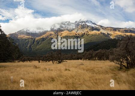 Vue sur une chaîne de montagnes enneigées dans des nuages au-dessus de l'endroit où Isengard a été filmé en trilogie LOTR, Fangorn sur la gauche, Rees Dart Track carpark, NZ Banque D'Images