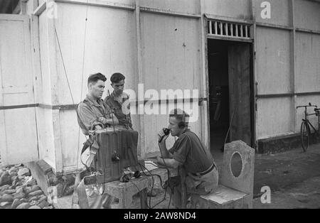 [Le soldat néerlandais communique par radio-téléphone, qui se trouve sur une table devant un bâtiment. Deux autres soldats écoutent] Date : janvier 1949 lieu : Indes orientales néerlandaises d'Indonésie Banque D'Images