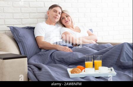 Couple romantique heureux ayant le petit déjeuner au lit à la maison Banque D'Images