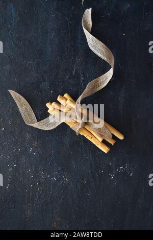 Gros plan de gressins joints avec un ruban sur fond sombre, vue de dessus, gressins italiens. Maison, cuit, soupe, restaurant, four Banque D'Images