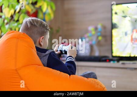 Jeune gamer garçon jouant en ligne jeu de course de voiture sur la nouvelle console à la télé à domicile Banque D'Images