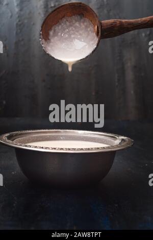 Pâte à crêpes mélangée à une louche en bois, pâte à crêpes de riz fermentée ou à dosa, nourriture indienne, concept de petit déjeuner indien du sud, pâte à base d'idli, régime alimentaire. Banque D'Images