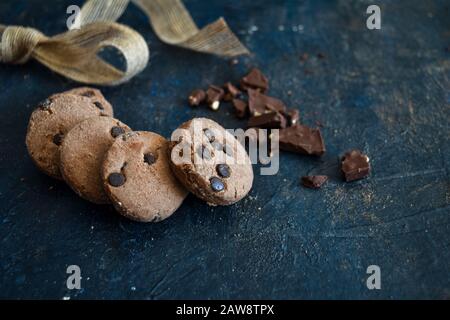 Petits gâteaux aux pépites de chocolat frais faits maison avec ruban et chocolat noir, sans gluten, café, boulangerie, vue de dessus sur un fond rustique sombre, espace copie. Banque D'Images