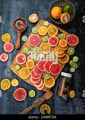 Vue de dessus de fruits mélangés en tranches d'agrumes, avec un couteau sur une planche à découper en bois. Mélange de fruits tropicaux (lime, citron, orange, pamplemousse), vue du dessus Banque D'Images