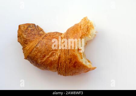 Mordre croissant sur fond blanc. Une tranche de croissant frais vue de dessus. Pâtisserie française avec croûte dorée pour le petit déjeuner. Rejet de régime de l'ap cuit Banque D'Images