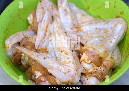 Ailes de poulet dans une marinade dans un bol en plastique vert. Ailes de poulet cru dans les épices. Banque D'Images
