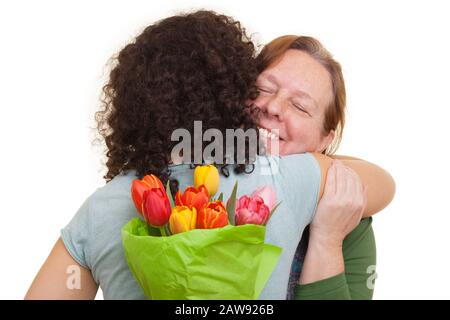 Jeune femme avec bouquet de tulipes dissimulées derrière sa femme âgée embrassant le dos, isolée sur fond blanc. Fête des mères, Saint Valentin, Pâques et Banque D'Images