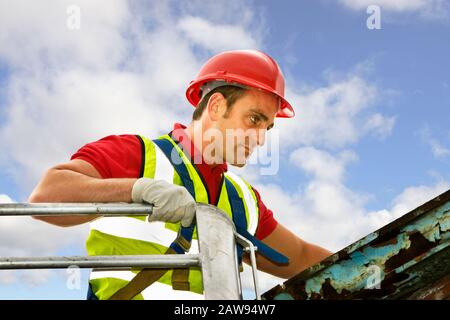 Ouvrier de la construction, homme, ouvrier dans un cueilleur de cerises portant des vêtements de sécurité et inspectant un toit sur un chantier de construction Banque D'Images
