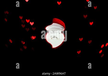 Boîte en velours rouge en forme de coeur avec anneau en losange sur fond noir tendance avec lumières bokeh. Cadeaux pour femme le jour de la Saint Valentin. Amour, concept de proposition. Banque D'Images