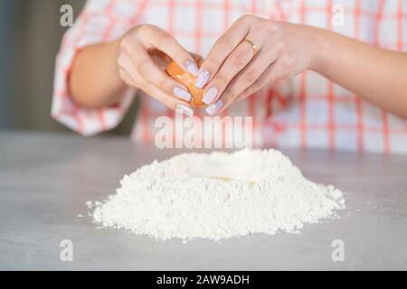 Femme ajoutant un œuf à un moulus de farine Banque D'Images