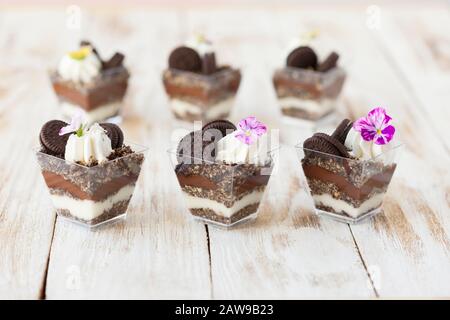 Trifle chocolat noir et blanc avec cookie. Décoré avec une fleur sur fond blanc vieux bois. Dessert sucré traditionnel anglais . Banque D'Images