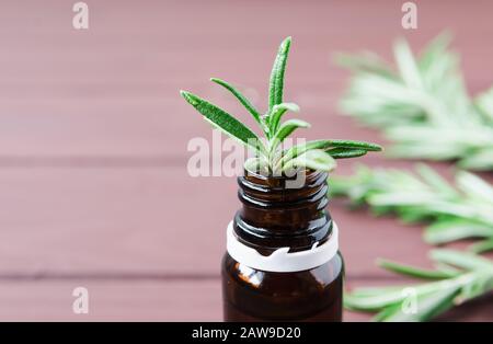 bouteille d'huile essentielle et de feuilles de romarin sur une table en bois brun Banque D'Images