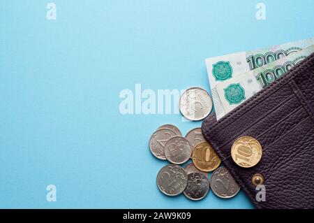 Roubles russes dans le portefeuille sur un fond bleu. Mille billets et différentes pièces. Banque D'Images