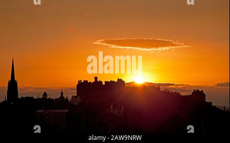 Edinburgh Castle, Écosse, Royaume-Uni. 7 février 2020. Le soleil se cache derrière une silhouette du château d'Édimbourg et du Hub, lors d'une soirée d'hiver calme et fraîche. Banque D'Images