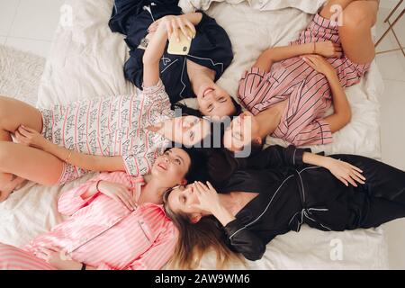 Jolies filles en pyjama avec selfie sur le lit. Banque D'Images