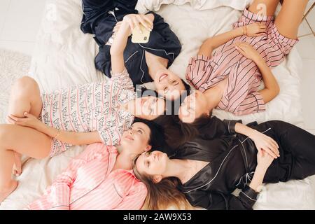 Jolies filles en pyjama avec selfie sur le lit. Banque D'Images