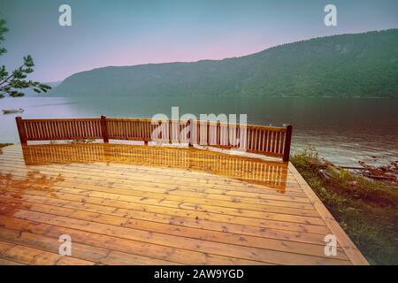 Terrasse en bois humide sur un lac. Côte rocheuse du lac de montagne dans la matinée pluvieuse d'automne. Belle nature de la Norvège. Banque D'Images