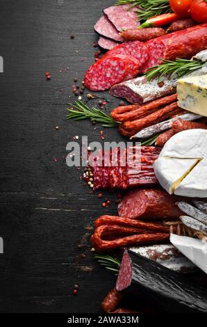 Assortiment de fromages, salami, saucisses, épices et produits à base de viande, sur fond noir. Vue de dessus. Espace libre pour votre texte. Banque D'Images