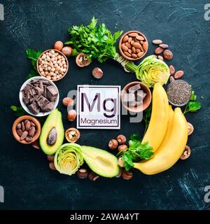 Aliments contenant du magnésium naturel. Mg : chocolat, banane, cacao, noix, avocats, brocoli, amandes. Vue de dessus. Sur fond noir. Banque D'Images