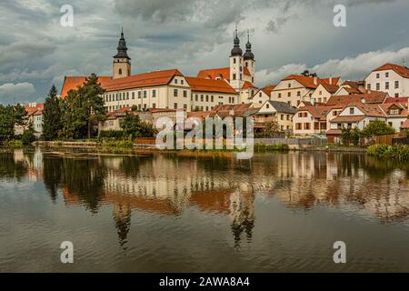 Telc / République tchèque - 27 septembre 2019: Vue sur le château, la tour de l'église de James le Grand et les maisons historiques sur un lac. Banque D'Images