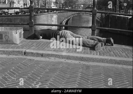 Homme allongé sur des feux de signalisation pour l'éclairage de fête à Amsterdam Date: 26 avril 1974 lieu: Amsterdam, Noord-Holland mots clés: Ponts, illuminations, hommes Banque D'Images