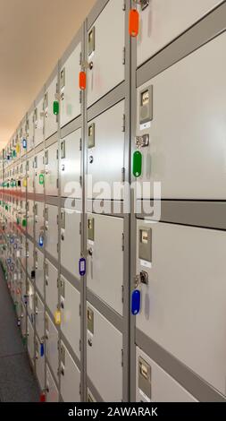 Rangée de petits casiers personnels industriels avec leurs clés accrochées dans un couloir d'entrepôt Banque D'Images