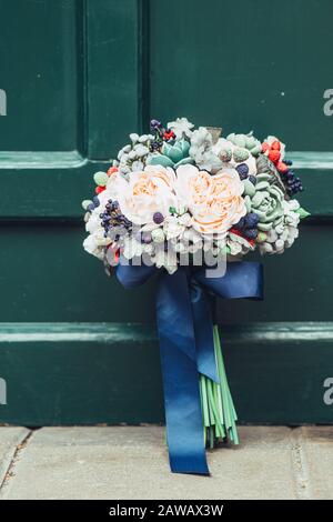 Fleurs faites à la main en argile polymère japonaise. Ils ressemblent à un véritable bouquet de mariage. Sur le fond d'une porte en bois vert Banque D'Images