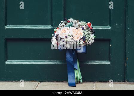 Fleurs faites à la main en argile polymère japonaise. Ils ressemblent à un véritable bouquet de mariage. Sur le fond d'une porte en bois vert Banque D'Images