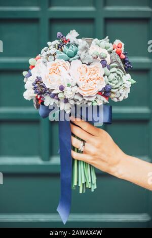 Fleurs faites à la main en argile polymère japonaise. Ils ressemblent à un véritable bouquet de mariage. Sur le fond d'une porte en bois vert Banque D'Images