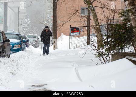 Montréal Québec Canada le 6 février 2020 : homme âgé de canne marchant sur une route enneigée pendant une tempête de neige Banque D'Images