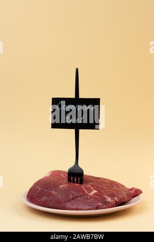 Une fourche est coincée dans un morceau de viande crue. Filet de veau. Étiquette de régime de carnivore. Concept de régime zéro carb. Banque D'Images