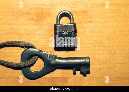 Ancienne clé avec petite serrure isolée sur fond de bois. Concept de sécurité et de sécurité Banque D'Images