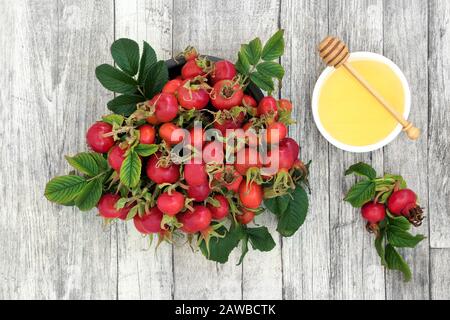 Fruits de baies de rosehip super nourriture utilisée dans la médecine de fines herbes pour le froid et la grippe remède avec le miel. Nourriture de santé très élevée en antioxydants et en vitamine c. Banque D'Images