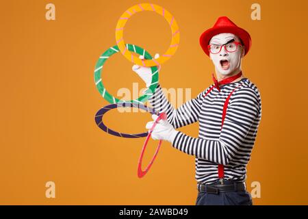 MIME MAN avec anneaux multicolores sur fond orange vide Banque D'Images