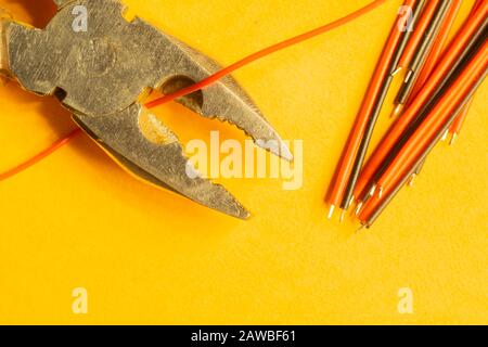 Pince coupe un fil rouge sur fond jaune. Outil de travail. Espace de copie Banque D'Images