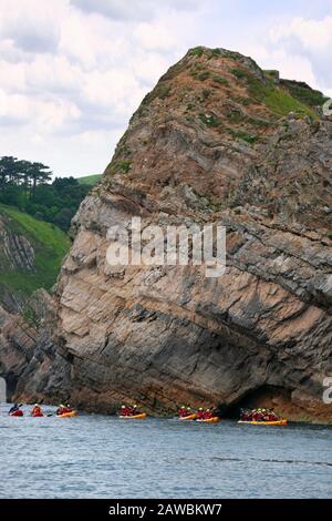 Lulworth Cove, Dorset: Les falaises à l'entrée de la crique, avec les canoéistes passant une journée calme Banque D'Images