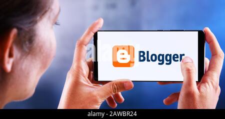 Poznan, POL - JUL 10, 2019: Femme tenant smartphone affichant le logo de Blogger, un service de publication de blogs qui permet des blogs multi-utilisateurs avec Time-stam Banque D'Images
