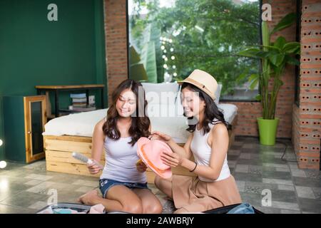 Deux jeunes amis asiatiques emportant un sac de voyage avant de partir en vacances. Amitié. Voyage. Vacances Banque D'Images
