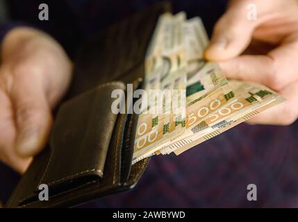 Portefeuille en cuir marron avec billets sur une ancienne surface en bois. Gros plan. Banque D'Images