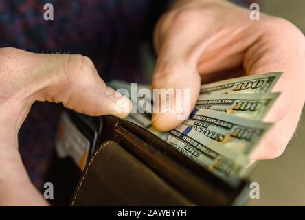 Portefeuille en cuir marron avec des dollars dans les mains. Gros plan. Banque D'Images