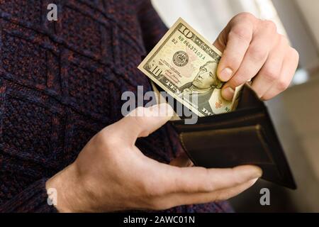 Portefeuille en cuir marron avec des dollars dans les mains. Gros plan. Banque D'Images