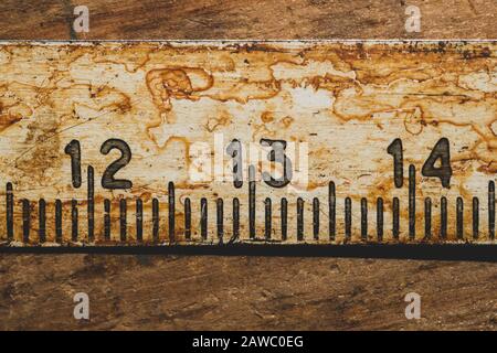 Ancienne règle rouillée avec numéros noirs sur une table en bois en état de marche. Ruban de mesure vintage gros plan. Milieu industriel. Atelier de menuiserie Banque D'Images