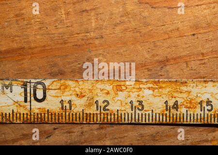 Ancienne règle rouillée avec numéros noirs sur une table en bois en état de marche. Ruban de mesure vintage. Arrière-plan industriel. Atelier de menuiserie avec espace de copie Banque D'Images