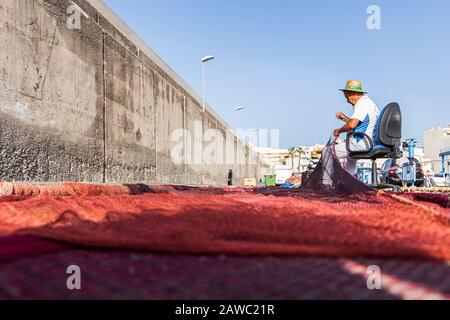 Pêcheurs réparant des filets de pêche sur le quai du port de Playa San Juan, Tenerife, îles Canaries, Espagne Banque D'Images